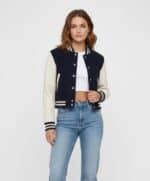 Casual varsity jacket with navy and cream design, paired with light blue jeans. Perfect for a trendy, sporty look.